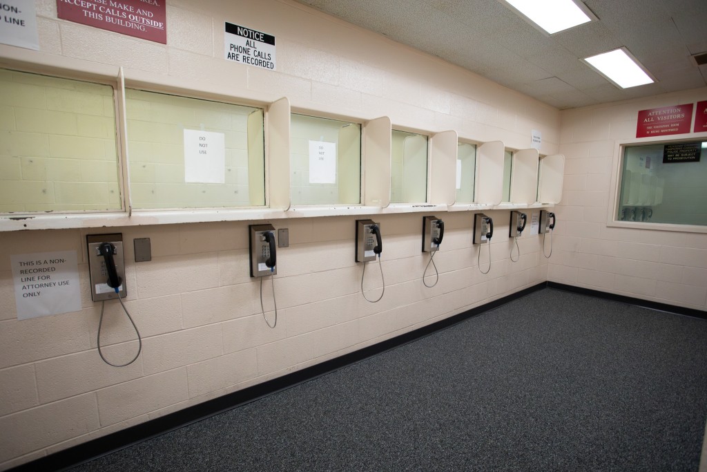 A row of telephones hangs from a beige, stone wall. A piece of paper taped next to the nearest phone reads "This is a non-recorded line for attorney use only."