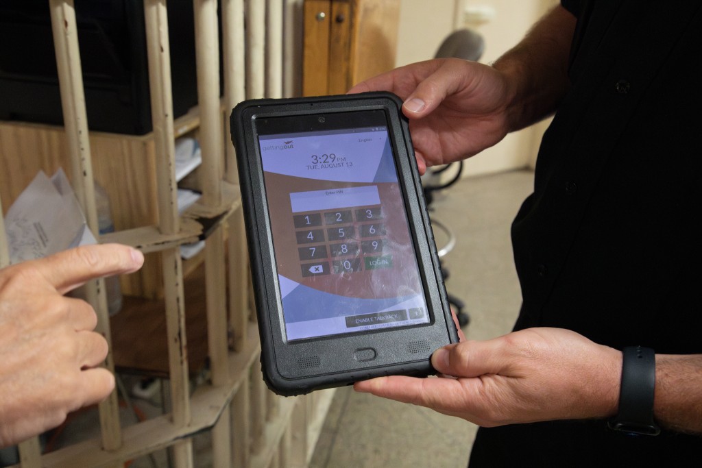 A man holds a tablet computer displaying a number pad.
