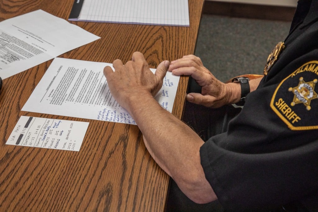 Sheriff Richard Fuller sits at a desk with an annotated copy of the county's contract with Global Tel-Link Corporation.
