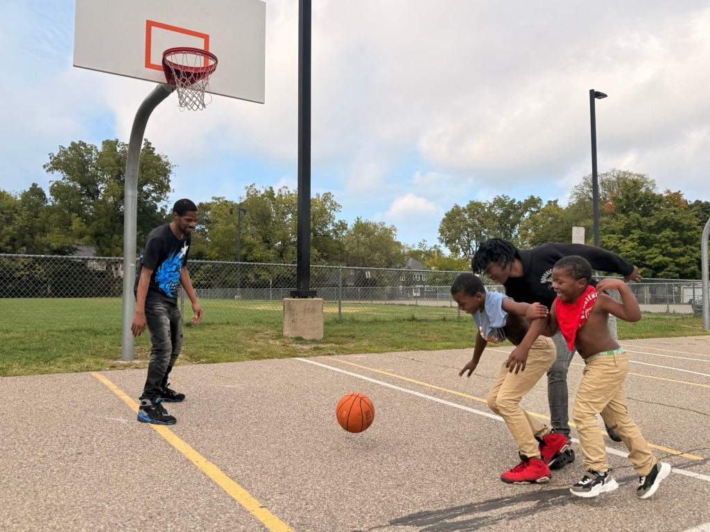 Dominic Deere laughs as his teenage son and two young nephews chase a basketball.